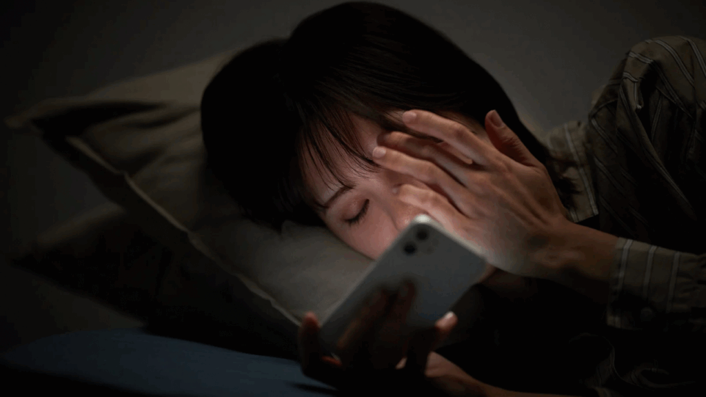 寝ながらスマホを見る女性